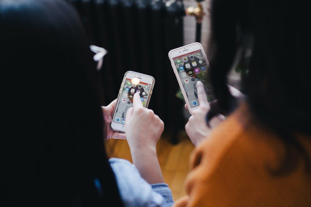 Two girls sharing and pointing at their phones