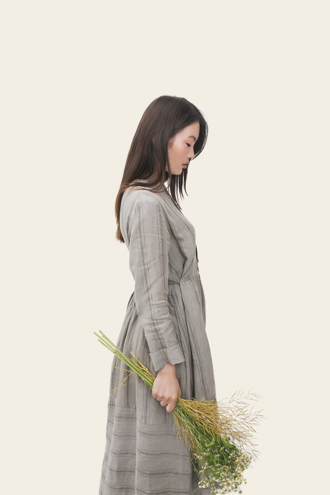 A woman looks down, forlorn, while holding a bunch of flowers.