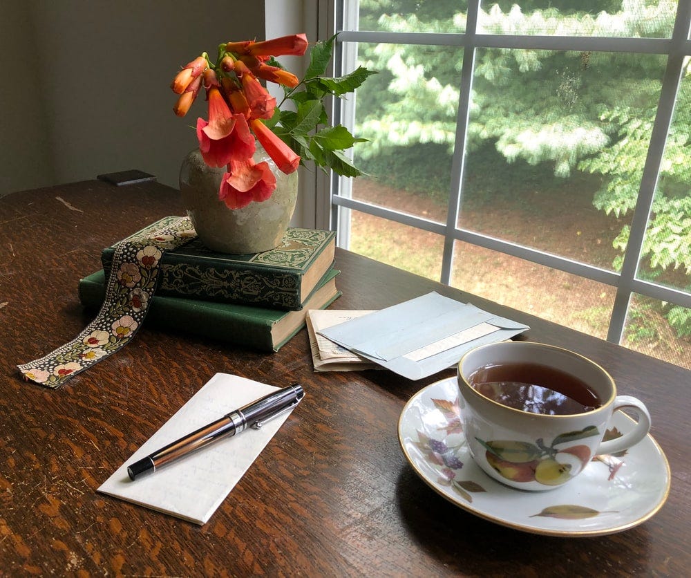 A cup of tea or coffee and a stack of letters on a desk.
