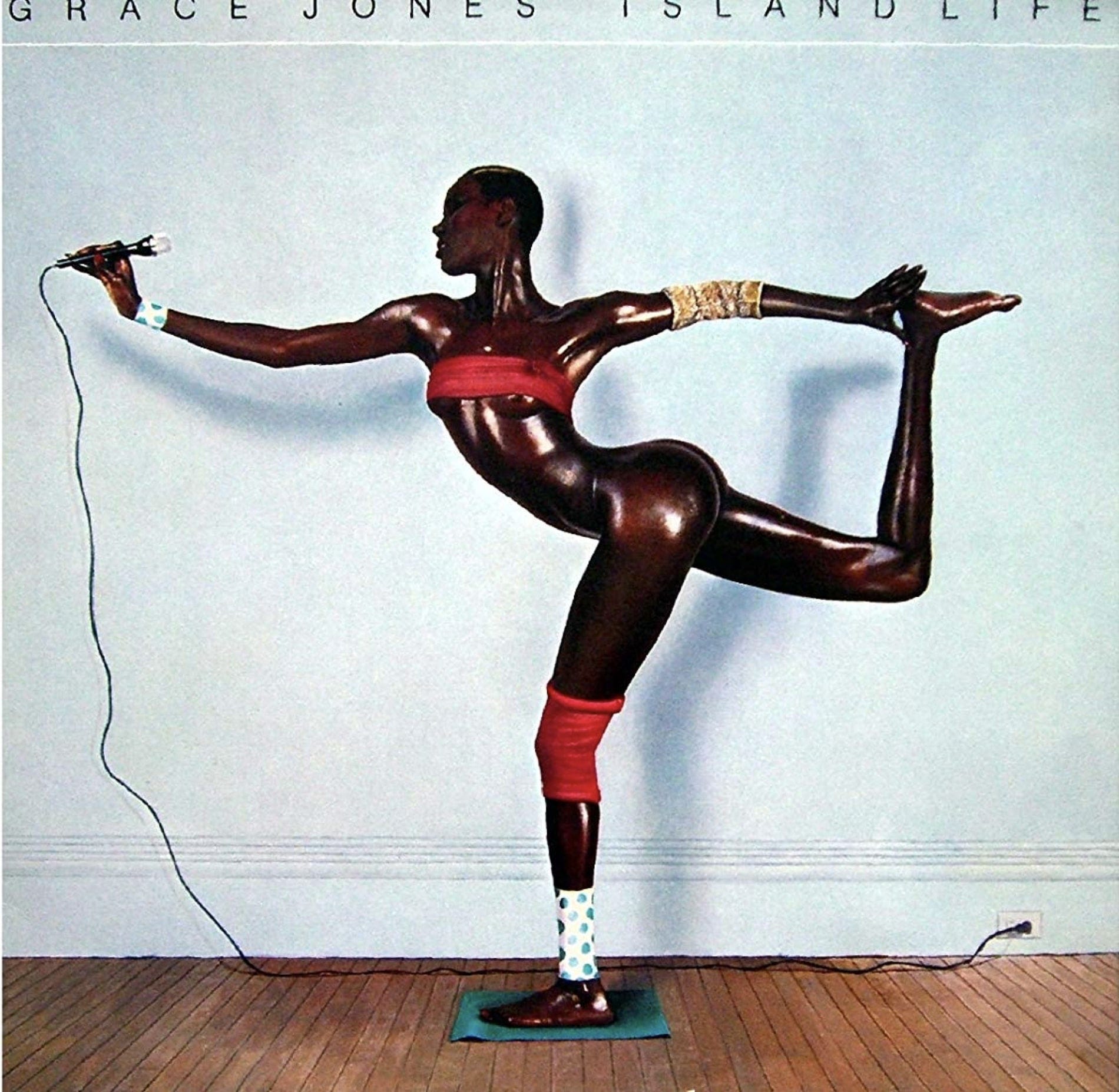 Artist Grace Jones stretches on the cover of her album, while singing into a microphone.