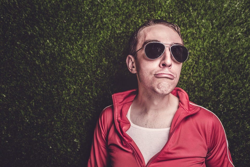 Man With Sunglasses Lying On Grass Squinting His Lips