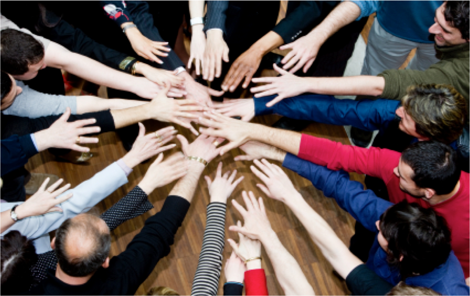 A circie of people putting their hands together in the middle of the circle
