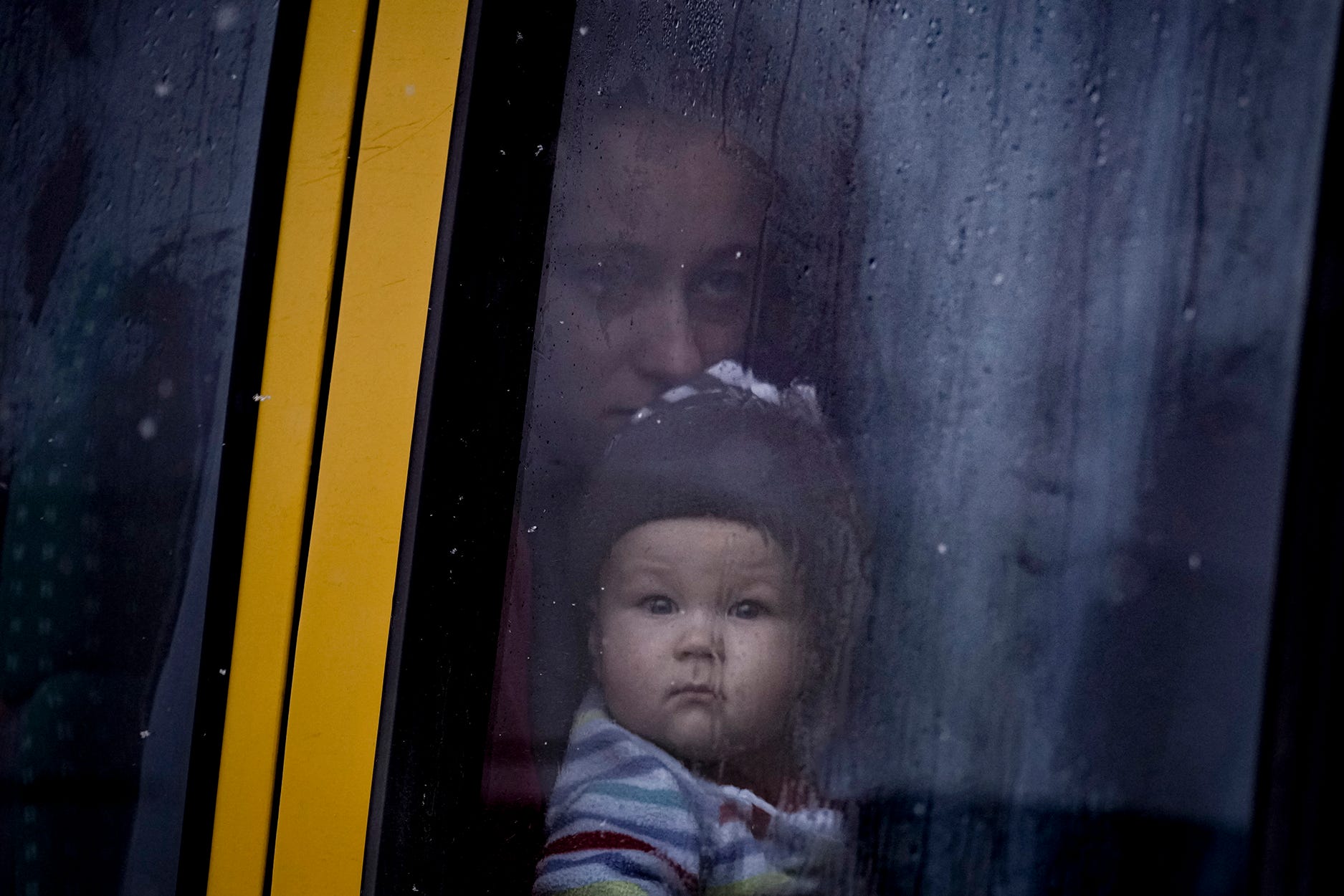 A woman and child, who were evacuated from areas on the outskirts of the Ukrainian capital, look out the window of a bus after arriving at a triage point in Kyiv, Ukraine, Weds., March 9, 2022. (AP Photo/Vadim Ghirda)