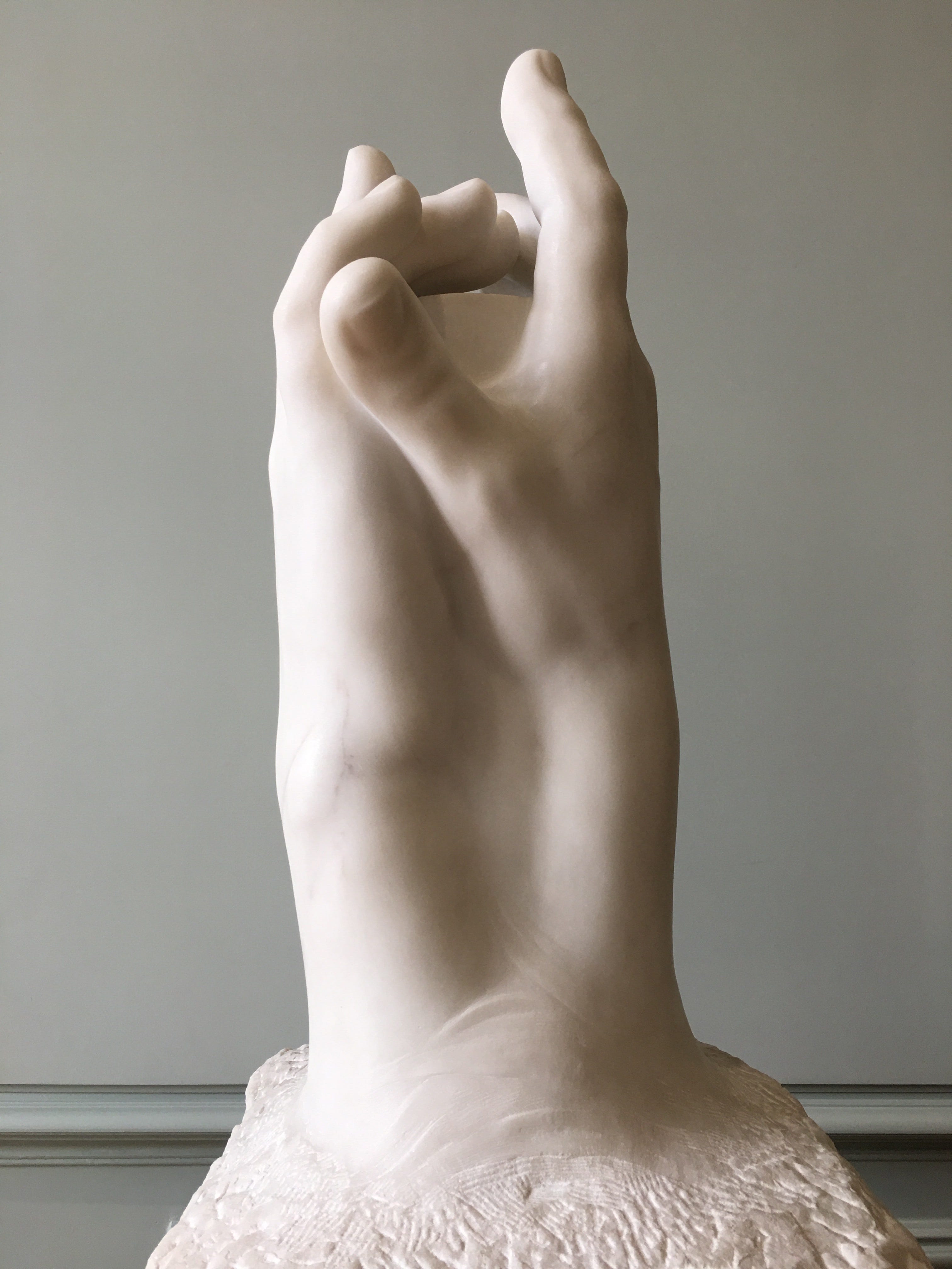 Two right hands in marble face one another touching at the fingers.