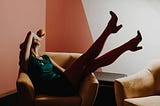 a woman laying back in a chair with her feet in the air.