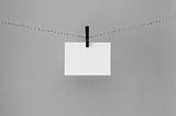 A blank white card is being held on a hanging line by a clip