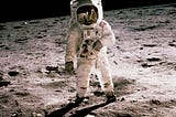 A man in an astronaut suit standing on the Moon. Soil is grey.