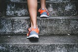 Person wearing sneakers running up stone steps