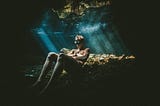 Swimmer sitting on the ocean floor contemplating