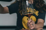 A woman pouring wine into a glass.