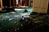 The floor of a home, covered in broken glass.