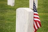 Image of a graveyard with tombstones and an American flag (signifying veterans laid to rest there)