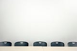 An empty board room table with chairs around it