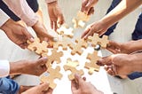 Company employees putting pieces of a jigsaw puzzle together