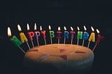 Cake with lit candles spelling out “Happy Birthday”.