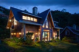 Cabin-style home exterior after sunset with lights on