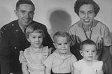 Photograph of the author’s family when he was two years old, with him and his sisters sitting in front of their smiling parents.