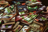 A table with a stack of unorganized books