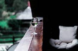 Glass of white wine on porch railing
