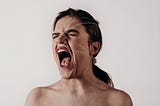 Young woman screaming whilst restrained by threads tied around her head