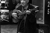 an old man playing his bouzouki