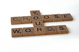 Scrabble letters arranged to spell “Choose Your Words”