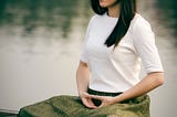 Women meditating by a lake