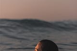 Woman swimming alone in the ocean at sunset