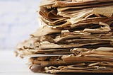Pile of ratty old manuscripts, torn, worn, creased. Yellowed paper. Seen from the side.