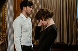 A photo of a man in a white shirt standing in front of a woman wearing a black dress.