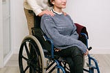 Man helps a woman sitting on a wheelchair