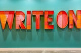 Art made out of hundreds of pencils spelling "WRITE ON". 