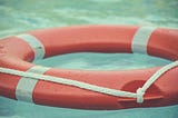 An orange and white life ring floating on water.