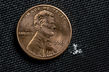 A small amount of white fentanyl is shown next to a much larger penny.