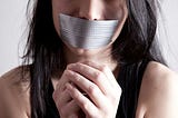 A woman with her hands tied and mouthe duct taped