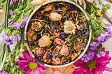 A container with herbs, flowers, plants and roots with various colors.