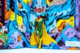 A vision action figure (a red robot in green jumpsuit with a yellow cape and boots)