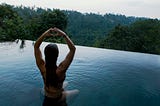 A woman in a swimming with her hands up and her finger folded into a love symbol