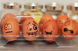 Image shows four brown eggs with faces drawn on them, looking (from left to right) worried, bemused, amused, and shocked.