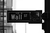 The image displays a sign on Wall Street in New York City. Invest Confidently with TYKR: A Guide to Managing Your Wealth and Achieving Early Retirement