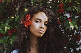 Beautiful woman of color with a red flower in her hair.