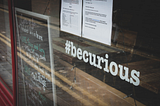 Store window with the hashtag “be curious” on the window