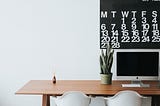 A plant on a wooden table with calendar for productivity