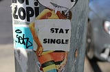 sticker on a lamp post that says ‘stay single’