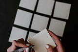A person’s hands laying sticky notes in a grid.