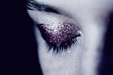 Close-up of a woman’s closed eye with glittery make-up.