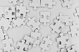 White puzzle pieces scattered on white background