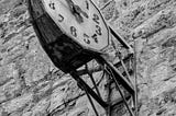 A black and white image of an old clock attached to a stone wall
