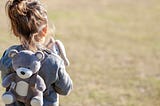 A little girl wearing a backpack outside.