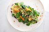 a white plate holding spinach salad